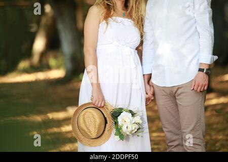 Un jeune couple romantique de beaux futurs parents faisant un grossesse photoshoot dans une forêt Banque D'Images