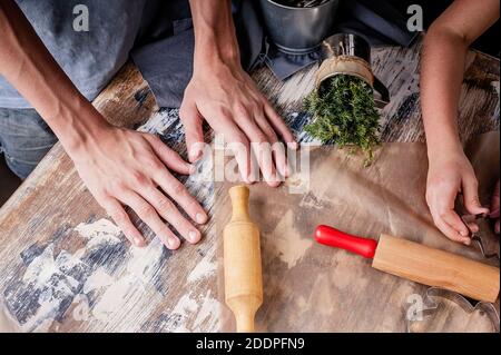 Moules et outils pour cuire des biscuits de Noël faits maison. Enfants mains sur le fond d'une table rustique. Délicieuses pâtisseries traditionnelles faites maison Banque D'Images