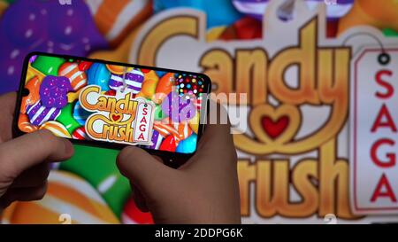 Nova Lima, Brésil - novembre 2020: Mains tenir un smartphone avec le JEU SAGA D'ÉCRASEMENT DE BONBONS dans L'ARRIÈRE-PLAN du grand écran Banque D'Images