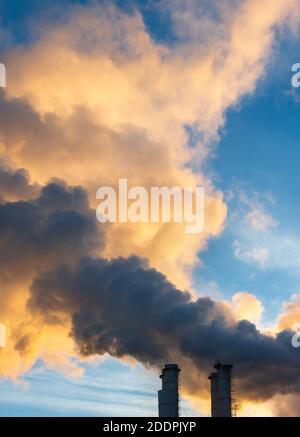 Cheminées industrielles qui déversons de la fumée et de la suie dans le ciel bleu polluer l'air et provoquer le réchauffement de la planète et le changement climatique avec les gaz à effet de serre et Banque D'Images