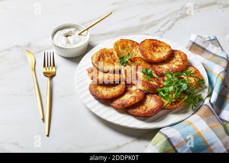 Crêpes de pommes de terre sans gluten avec fromage cottage à l'ail et au persil, servies avec une sauce à la crème sure sur une assiette sur fond de pierre en marbre clair avec Go Banque D'Images