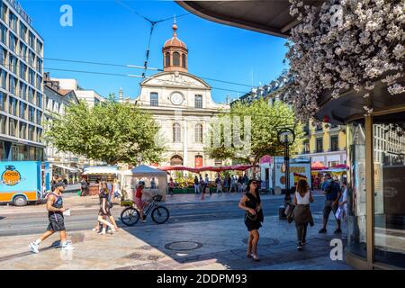 Les gens magasinent sur le marché de la place de la Fusterie, au pied de l'ancien temple devenu espace Fusterie, et dans la principale rue commerçante de Genève. Banque D'Images