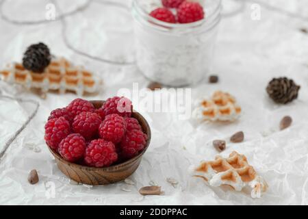 Fromage cottage avec framboises, muesli et gaufres, sur le yaourt dans un pot enveloppé dans un chandail blanc chaud. Banque D'Images