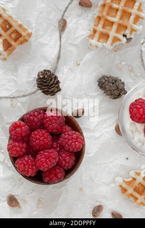 Fromage cottage avec framboises, muesli et gaufres, sur le yaourt dans un pot enveloppé dans un chandail blanc chaud. Banque D'Images