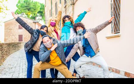 sourire heureux groupe d'amis s'amuser dans une ville rue portant des vêtements chauds d'hiver et un masque de protection pour le visage célébrez le verrouillage du coronavirus Banque D'Images