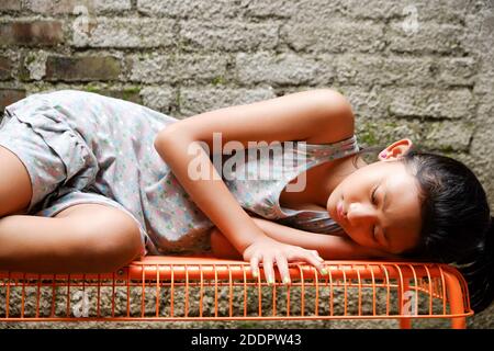 Une adolescente d'origine asiatique du Sud-est s'allonger sur un banc, bronzer le matin à la maison Banque D'Images