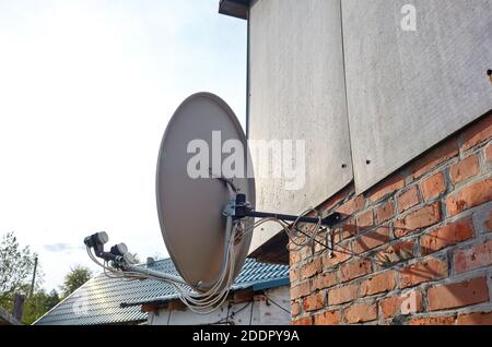 La parabole satellite est fixée au mur de la maison. Une installation de télévision par satellite sous le toit Banque D'Images