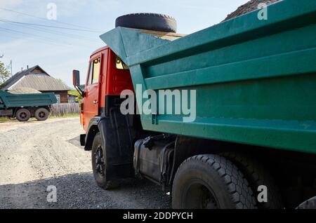 Grand camion à benne basculante sur la rue de banlieue. Attente de déversement de gravier pour la construction et la reconstruction de la chaussée Banque D'Images