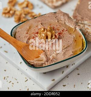 gros plan d'un bol avec un hummus appétissant, fait de pois chiches, de noix et de romarin, sur une table, à côté de quelques gâteaux de riz soufflé Banque D'Images