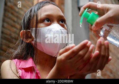 Jeune fille de l'Asie du Sud-est utilisant du gel liquide désinfectant pour les mains. Protection contre les virus infectieux hygiène et mode de vie sain. Banque D'Images