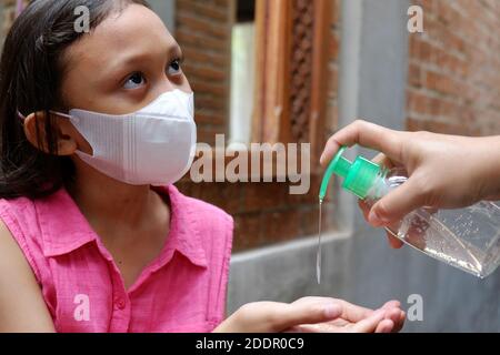 Jeune fille de l'Asie du Sud-est utilisant du gel liquide désinfectant pour les mains. Protection contre les virus infectieux hygiène et mode de vie sain. Banque D'Images
