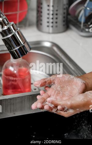 Gros plan image des mains lavées à l'aide de savon sous la douche d'eau sur un évier de cuisine pour la propreté et les soins de santé. Un mode de vie sain Banque D'Images