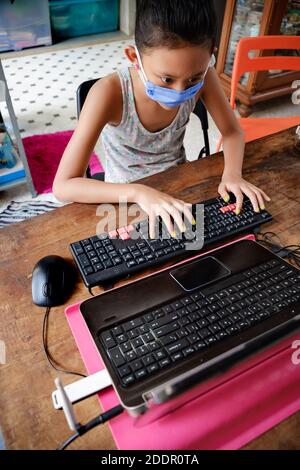 Asie du Sud-est Teenage Girl School étudiant portant masque de visage utilisation Ordinateur portable étudiant en ligne à la maison pendant la pandémie Covid-19 Banque D'Images