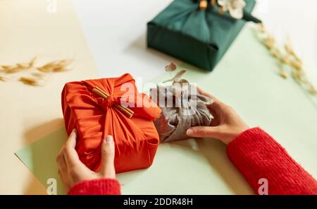 Les jeunes femmes ont mis en place des cadeaux enveloppés dans du tissu sur la table, Noël et le concept minimaliste du nouvel an. 4k Banque D'Images