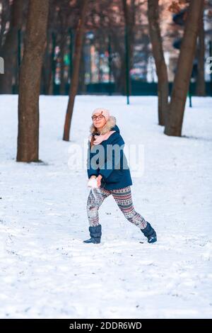 Bonne adolescente ayant un combat de boule de neige, prêt à jeter un boule de neige, jouant des boules de neige dans le parc d'hiver Banque D'Images
