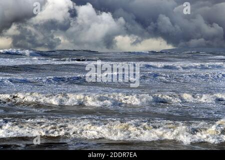 On voit ici des mers sauvages dans des vents de force gale au large de la côte d'Anglesey. Le ciel spectaculaire a été ajouté à l'aide de Photoshop. Banque D'Images