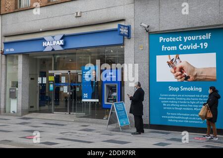 Slough, Royaume-Uni. 26 novembre 2020. Les membres du public portent des couvre-visage alors qu'ils font la queue à l'extérieur d'une succursale de la société de construction de Halifax, à Slough High Street. Le gouvernement britannique a annoncé que Slough allait passer au niveau 3, le plus haut niveau de restrictions concernant les coronavirus, lorsque le second verrouillage imposé pour aider à prévenir la propagation de COVID-19 prendra fin après le 2 décembre. Crédit : Mark Kerrison/Alamy Live News Banque D'Images