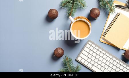 Bureau à la maison table avec tasse à café, clavier d'ordinateur, bloc-notes, presse-papiers, branches de pin et décorations de Noël. Flat lay, vue de dessus. Wint Banque D'Images