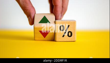 Les cubes de bois changent la direction d'une flèche symbolisant que les taux d'intérêt baisent ou vice versa. Main mâle. Affaires et taux d'intérêt Banque D'Images