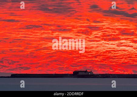 Charmouth, Dorset, Royaume-Uni. 26 novembre 2020. Un spectaculaire coucher de soleil rouge et flamboyant au-dessus du port de Cobb et de Lyme Regis à Dorset vu de la plage à Charmouth à la fin d'une journée ensoleillée crédit photo: Graham Hunt/Alamy Live News Banque D'Images