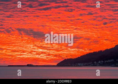 Charmouth, Dorset, Royaume-Uni. 26 novembre 2020. Un spectaculaire coucher de soleil rouge et flamboyant au-dessus du port de Cobb et de Lyme Regis à Dorset vu de la plage à Charmouth à la fin d'une journée ensoleillée crédit photo: Graham Hunt/Alamy Live News Banque D'Images