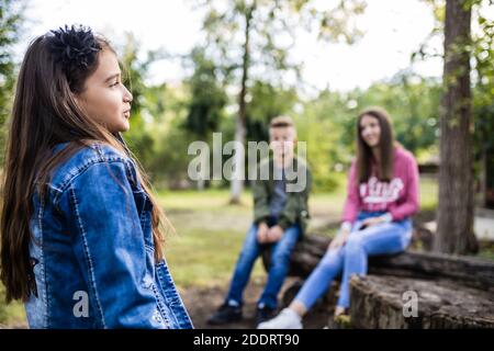 Portrait d'une fillette heureuse tout en parlant avec vos amis dans le parc Banque D'Images