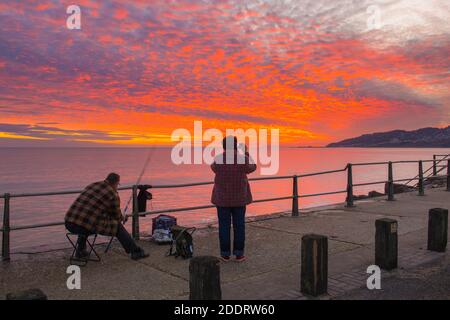 Charmouth, Dorset, Royaume-Uni. 26 novembre 2020. Un couple regardant le spectaculaire coucher de soleil rouge et flamboyant à Charmouth à Dorset à la fin d'une journée ensoleillée. Crédit photo : Graham Hunt/Alamy Live News Banque D'Images