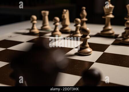 Jouer vieux échecs sur une table carrée dans un damier brun, figures de pions et de freux, reines et rois, chevaux table dans le noir, élégant pour adv Banque D'Images