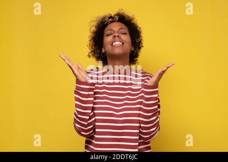 Joyeuse et heureuse jeune femme afro-américaine s'est jointe à la main, remerciant pour Bonne chance. Prière féminine souriante ethnique millénaire en attente de miracle. Banque D'Images