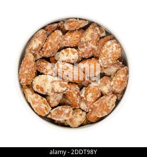 Amandes confites dans un bol blanc. Fait maison, d'une manière spéciale amandes cuites, noix entières enrobées de sucre croquant. Vendu sur les marchés de Noël. Banque D'Images