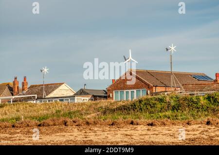 Petites éoliennes domestiques sur des chalets derrière la plage à Snettisham, sur la rive est du Wash, Norfolk. Banque D'Images