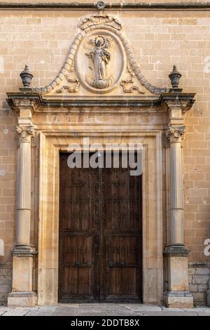 Porte principale de l'église dans la ville de Porreres. Grande porte en bois avec une pierre sculptée relief de la Vierge Marie avec l'enfant Jésus et l'ange Banque D'Images