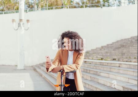 Une jeune femme télécharge l'application pour utiliser le scooter électrique en ville rue saine style de vie durable style de vie Banque D'Images