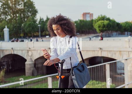 Une jeune femme télécharge l'application pour utiliser le scooter électrique en ville rue saine style de vie durable style de vie Banque D'Images