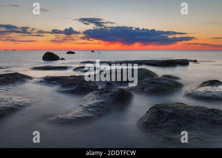 Magnifique coucher de soleil coloré sur la mer et les rochers. Mer Baltique. Estonie. Exposition longue. Banque D'Images