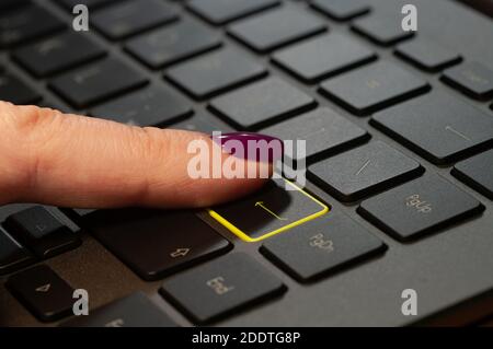 Gros plan du doigt de la femme en appuyant sur la touche entrée du clavier de l'ordinateur portable. Banque D'Images