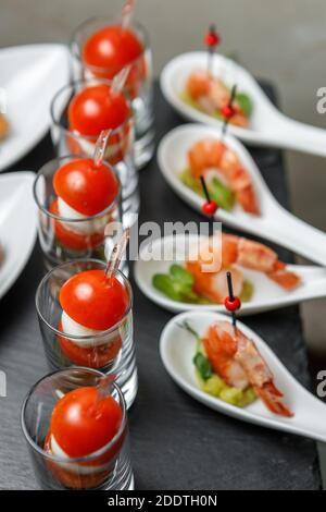 Tomates cerises et canapés mozzarella sur brochettes dans un verre verre avec un fond de crevettes royales en gros plan Banque D'Images