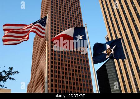 États-Unis d'Amérique, État du Texas, Houston. Centre-ville. Drapeaux des États-Unis, de l'État du Texas et de la ville de Houston. En arrière-plan, vue du TC Energy Center, anciennement connu sous le nom de Bank of America Center. Gratte-ciel postmoderne terminé en 1983. Il a été conçu par les architectes Philip Johnson et John Burgee. Banque D'Images