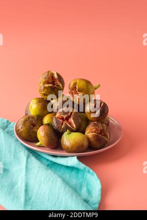 Beaucoup de figues sont sur une plaque rose à côté d'une plaque de lin turquoise. Fruits mûrs. Verticale Banque D'Images