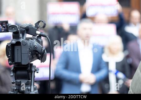 Concentrez-vous sur la caméra vidéo filmant la conférence de presse, groupe flou de personnes tenant des affiches de protestation en arrière-plan Banque D'Images