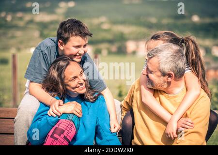 Famille heureuse sur le banc - Père, mère, fils et fille appréciant leur temps ensemble dans la campagne Banque D'Images