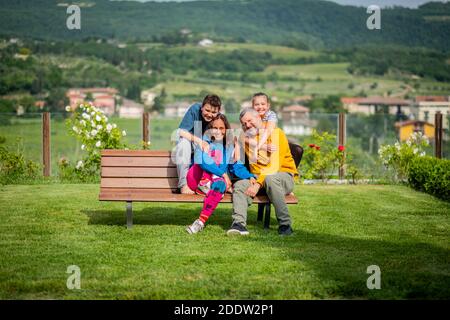 Famille heureuse sur le banc - Père, mère, fils et fille appréciant leur temps ensemble dans la campagne Banque D'Images