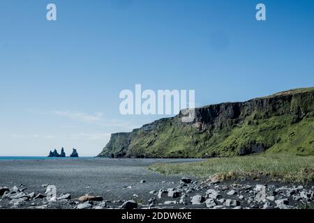 Reynisdrangar rock formations viewed from the town of Vík in South Iceland on a sunny, summer day. Stock Photo