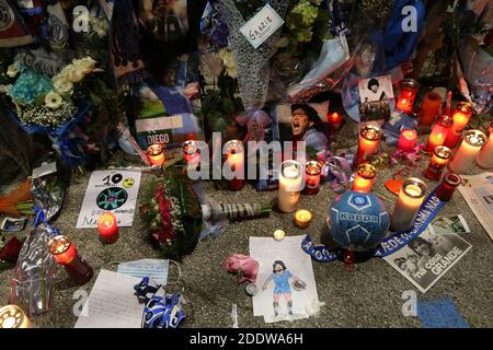 Naples, Italie. 26 novembre 2020. Un supporter rend hommage aux hommages laissés sur les clôtures en face du stade de San Paolo lors du deuil de la mort du footballeur Diego Armando Maradona le 26 novembre 2020 à Naples, en Italie. Diego Armando Maradona est mort à l'âge de 60 ans après un arrêt cardiaque alors qu'il était à son domicile à Tigre, en Argentine, où il convalescing après une opération cérébrale trois semaines plus tôt. Crédit : Agence photo indépendante/Alamy Live News Banque D'Images