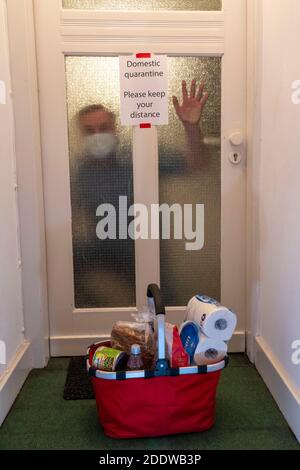 Image symbolique quarantaine domestique, homme suspecté d'infection corona, à la maison isolée, signe d'avertissement pour les visiteurs à la porte plate, communiqué Banque D'Images