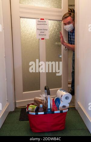 Image symbolique quarantaine domestique, homme suspecté d'infection corona, à la maison isolée, signe d'avertissement pour les visiteurs à la porte plate, communiqué Banque D'Images