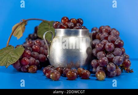 Fruits de raisin. Ingrédient pour les jus et le vin. Baies de raisin dans un récipient en aluminium. Arrière-plan bleu. Nourriture humaine Banque D'Images