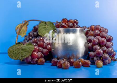Fruits de raisin. Ingrédient pour les jus et le vin. Baies de raisin dans un récipient en aluminium. Arrière-plan bleu. Nourriture humaine Banque D'Images