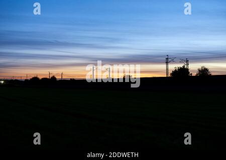 Coucher de soleil sur le chemin de fer électrifié de la côte ouest du chemin de fer principal avec le brin de chemin de fer faisant une silhouette au coucher du soleil Banque D'Images