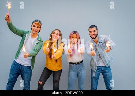 Groupe d'amis multiethniques qui se dansent avec des spameurs - des gens dansant Avec des barboteurs dans les mains - petit coup de jeune les gars qui tiennent les lumières du bengale à Banque D'Images